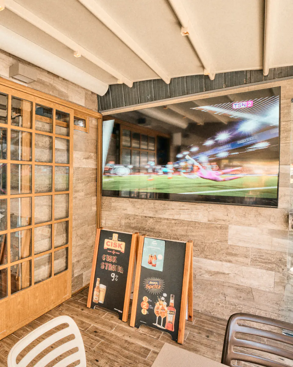 The terrace's biggest screen beside the door into the bar, a keeper diving on the match
