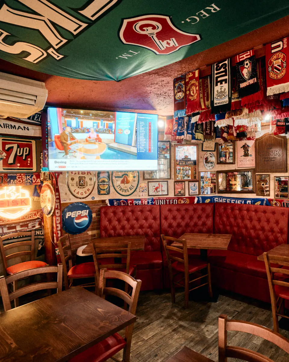 Red leather booths under the scarves, with the Premier League table on the screen