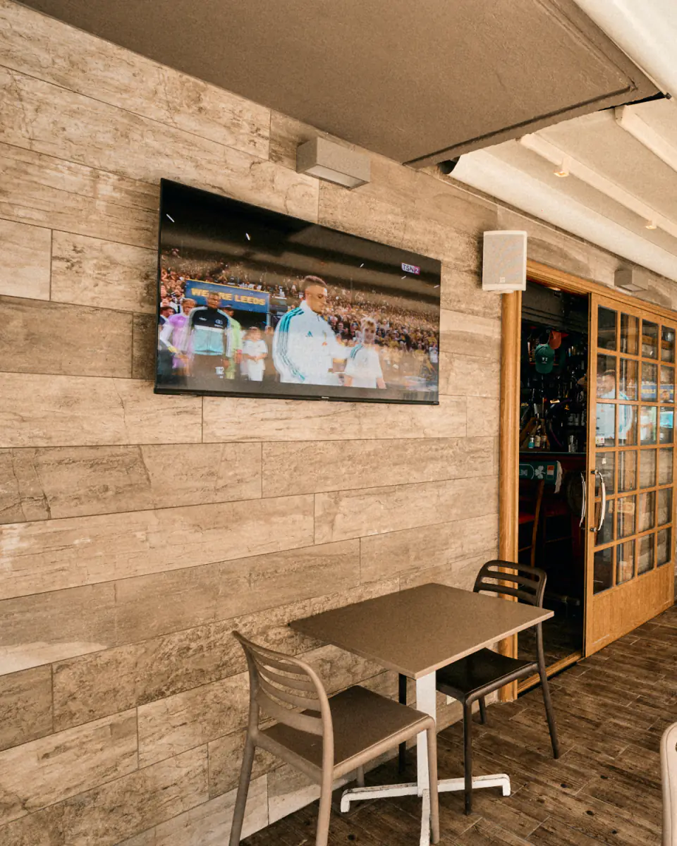 The covered terrace, with a screen either side of the door showing the same match