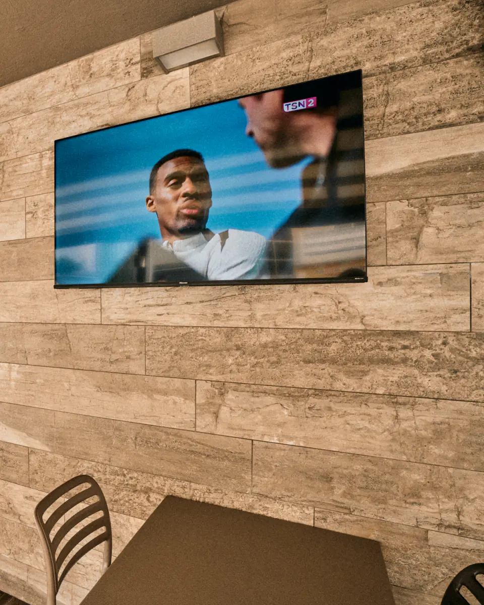 A large screen on the terrace's stone-clad wall above the tables